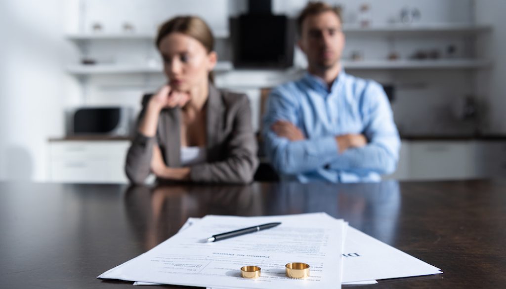 selective focus of couple sitting at table with divorce documents